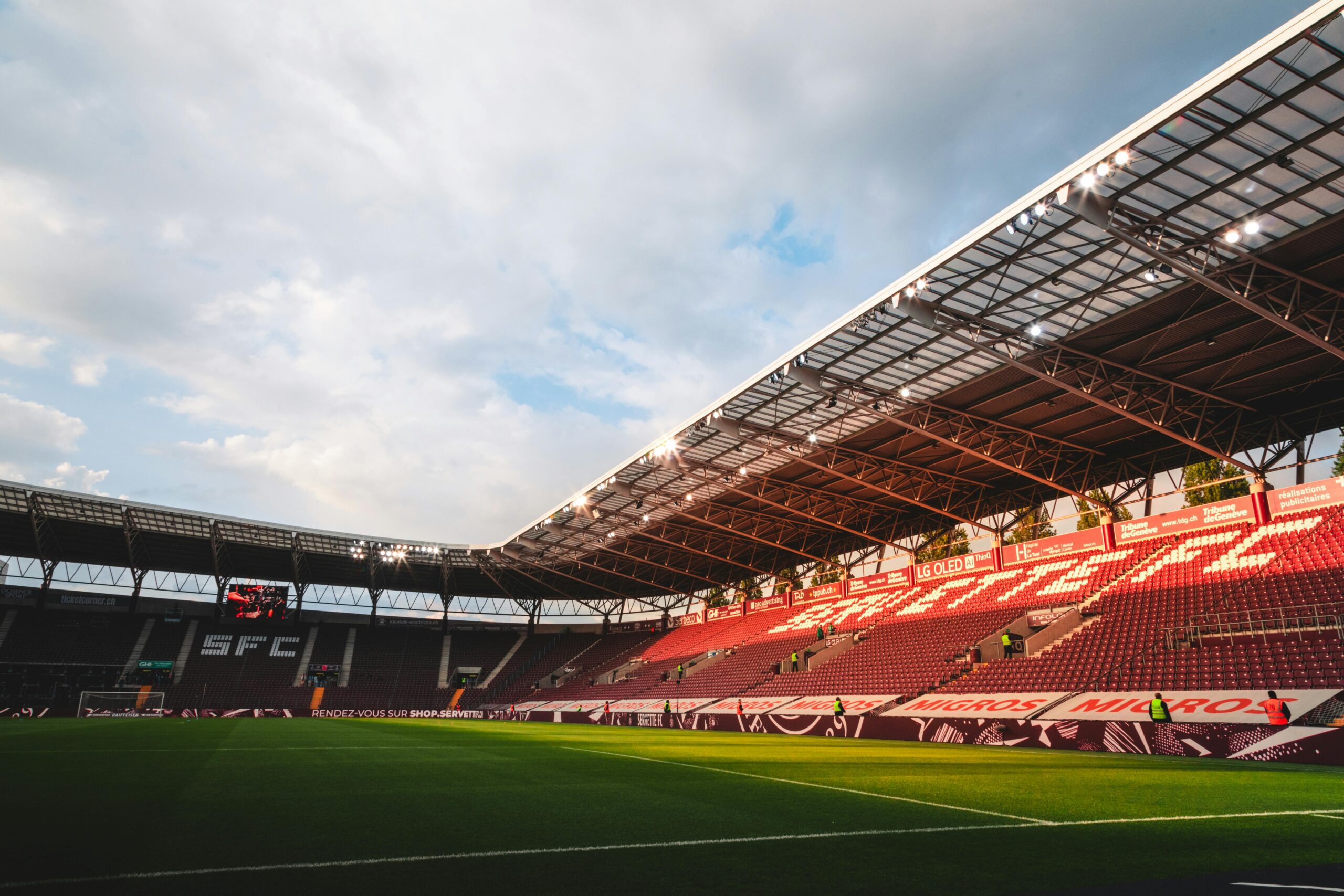 Wide-angle shot of Geneva's SFC stadium with empty seats and sky highlights.