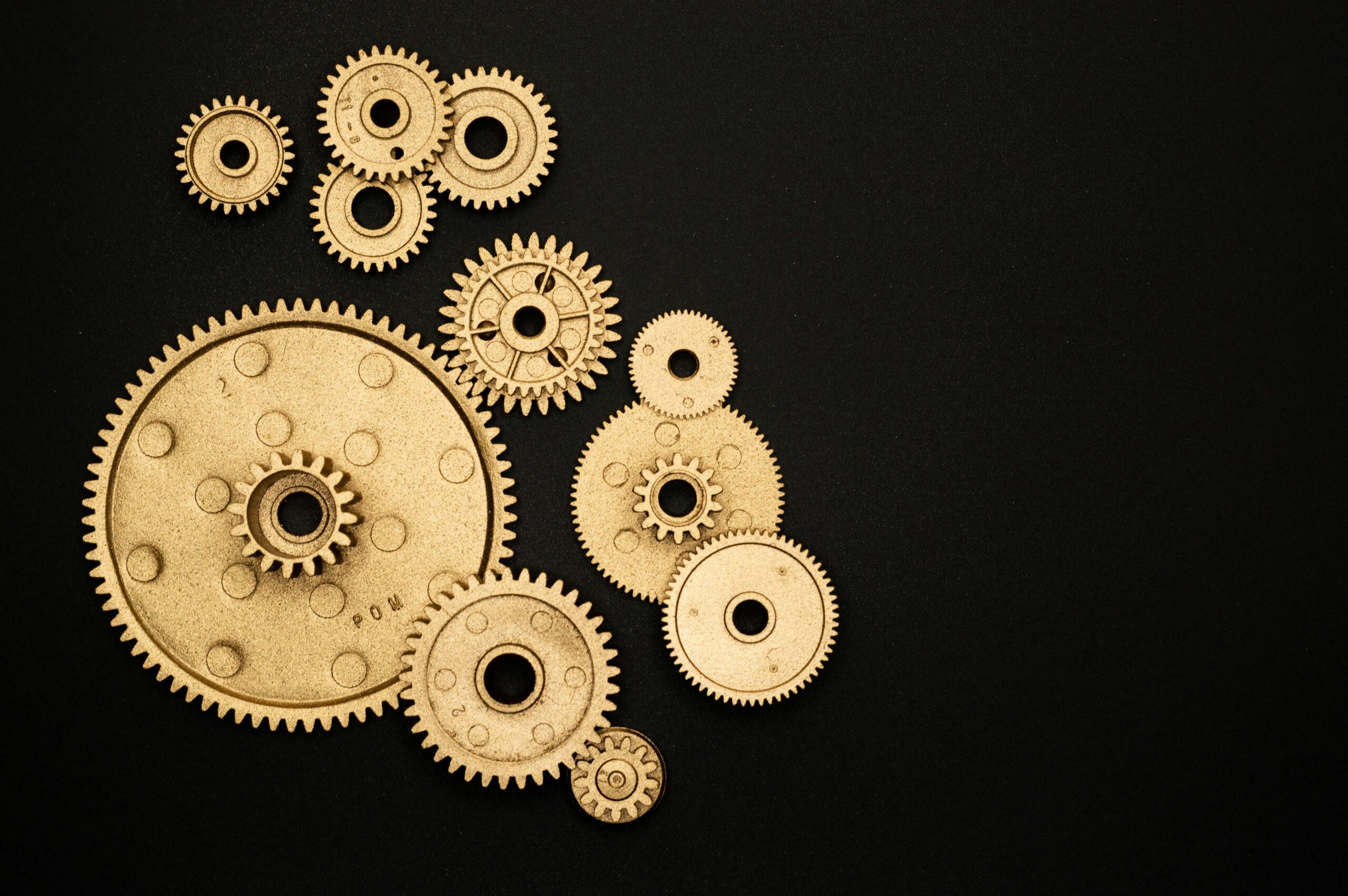 Close-up of gold gears arranged on a black backdrop, symbolizing teamwork and technology.