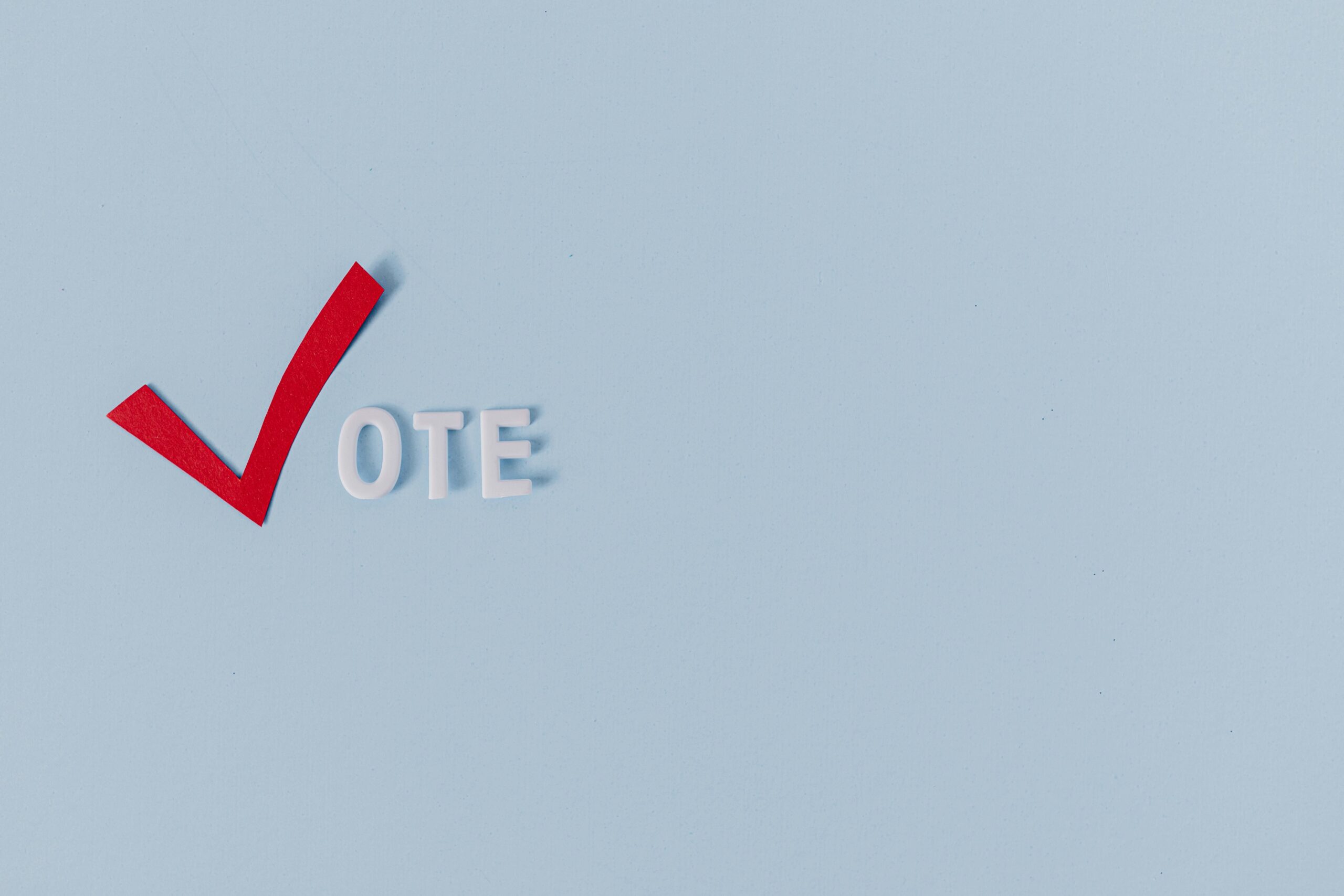 Red checkmark and 'vote' text on light blue background, symbolizing election and political choice.