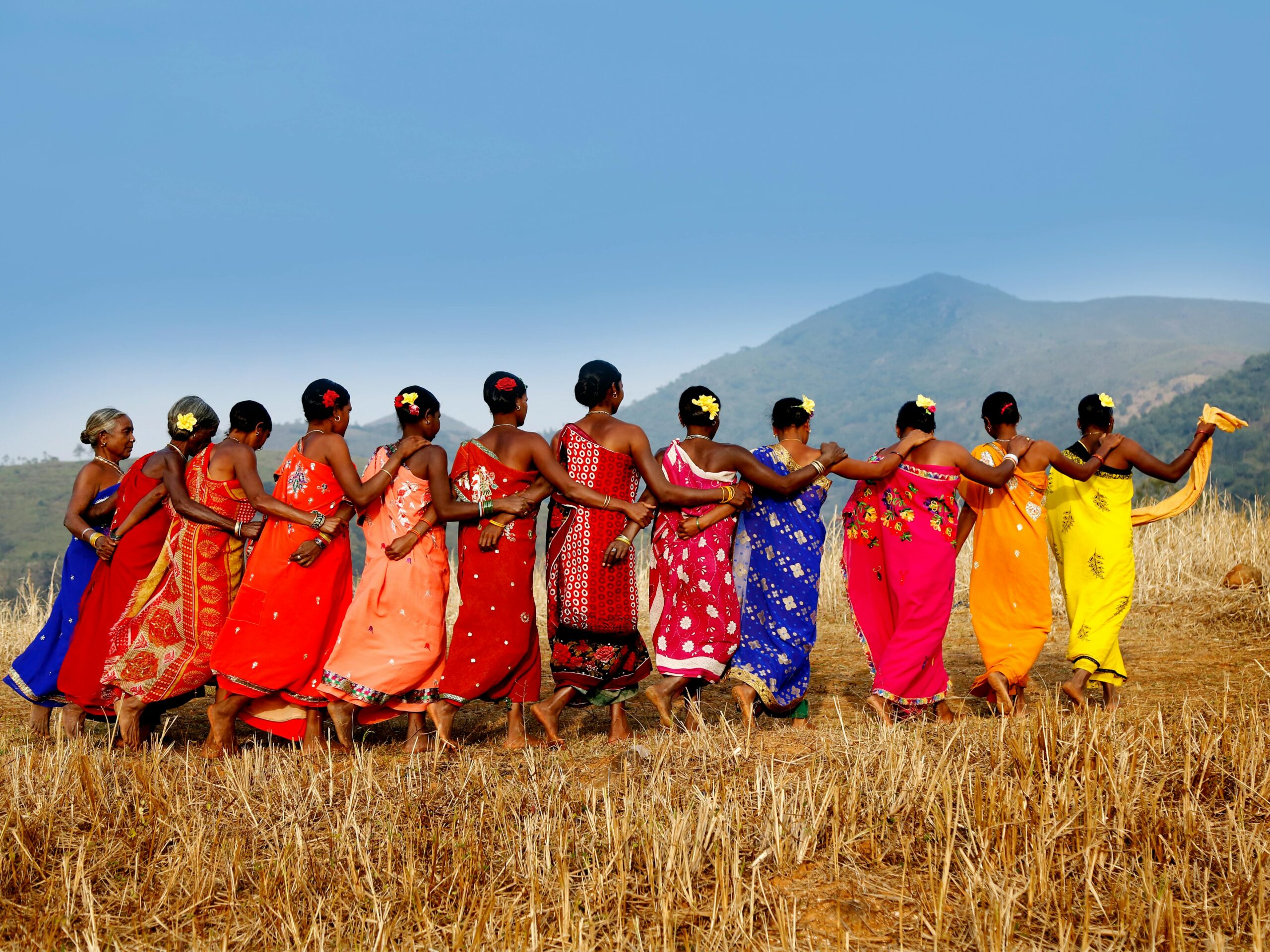 A vibrant display of cultural celebration with tribal women dancing in Araku Valley, India.